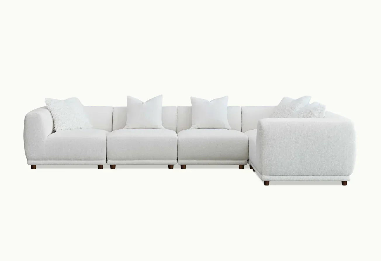 White corner sofa with modular sections and plush cushions on wooden legs