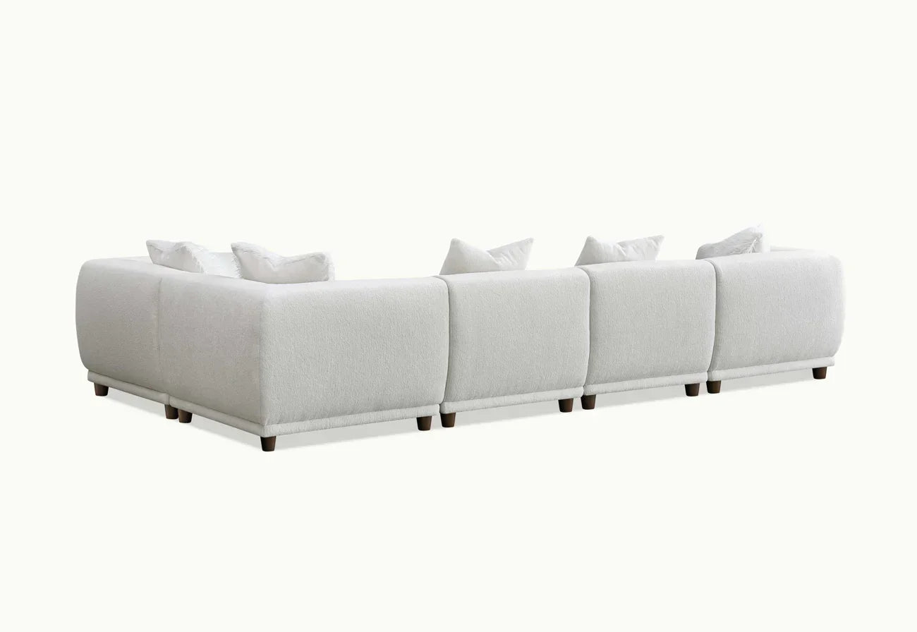 Back view of large white corner sofa with low wooden legs and scatter cushions