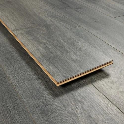 Grey oak laminate flooring plank with wood grain pattern on matching floor background