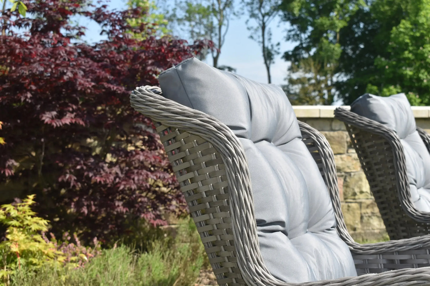 Grey rattan garden chair with padded cushion in outdoor patio setting