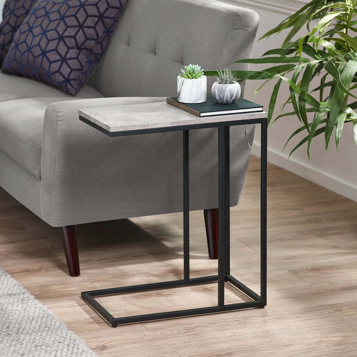 Staten drinks table with black metal frame beside grey sofa on wooden floor