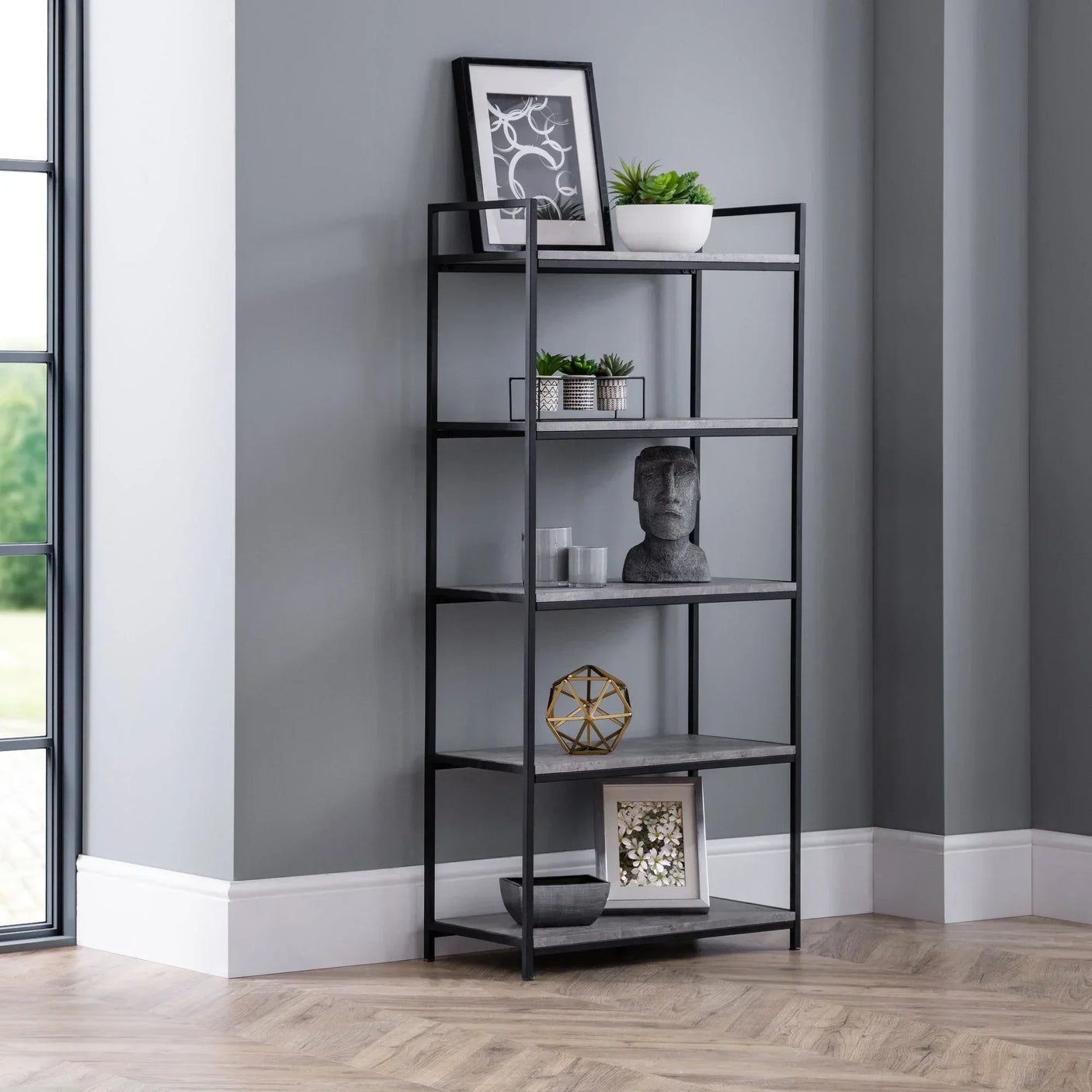 Tall black metal bookcase with grey shelves styled in modern living room corner