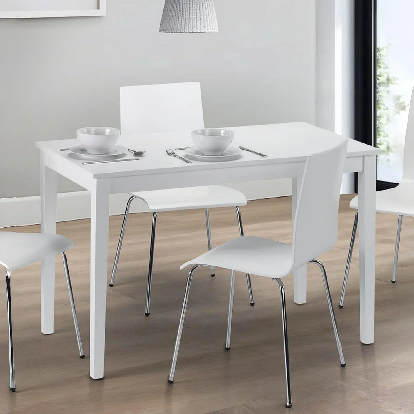 White dining table and four white chairs with chrome legs on wooden floor