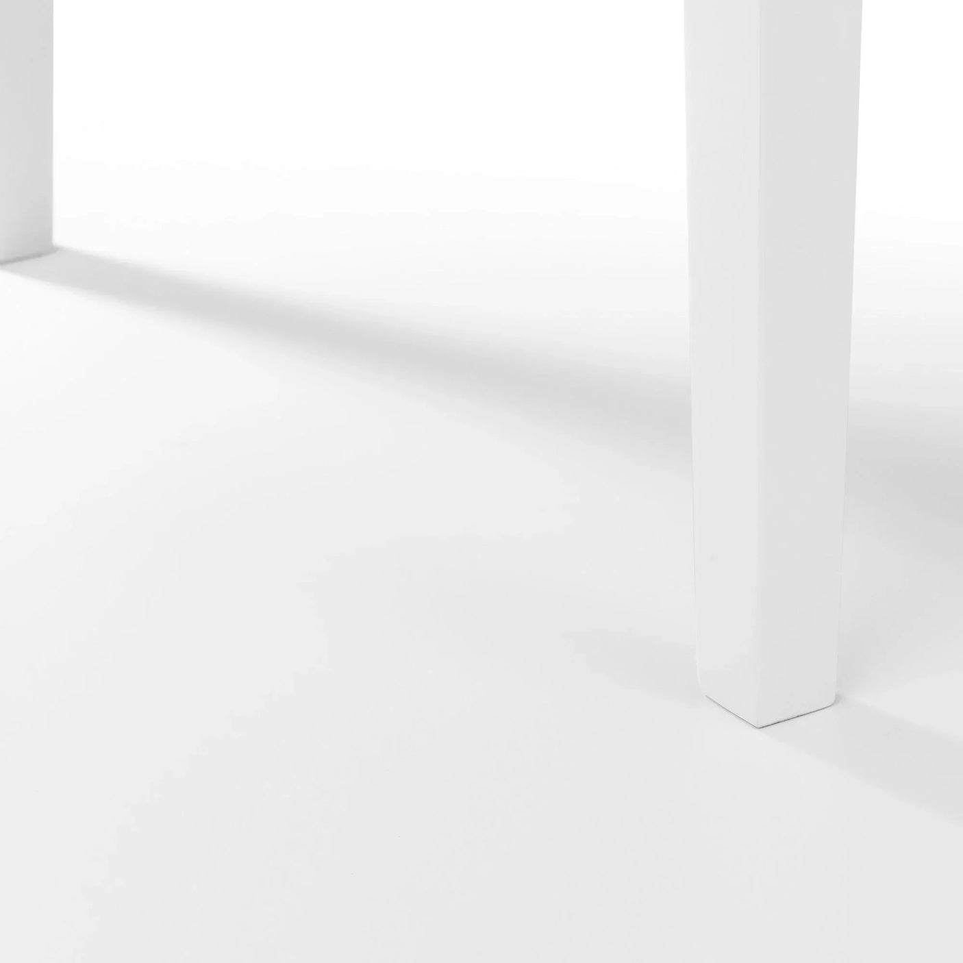 Close up of white dining table legs on clean white floor