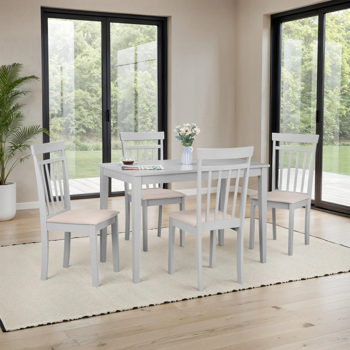 Light grey wooden dining table set with four chairs on cream rug in modern dining room