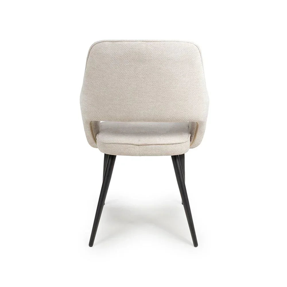 Beige fabric dining chair with black legs shown from the back