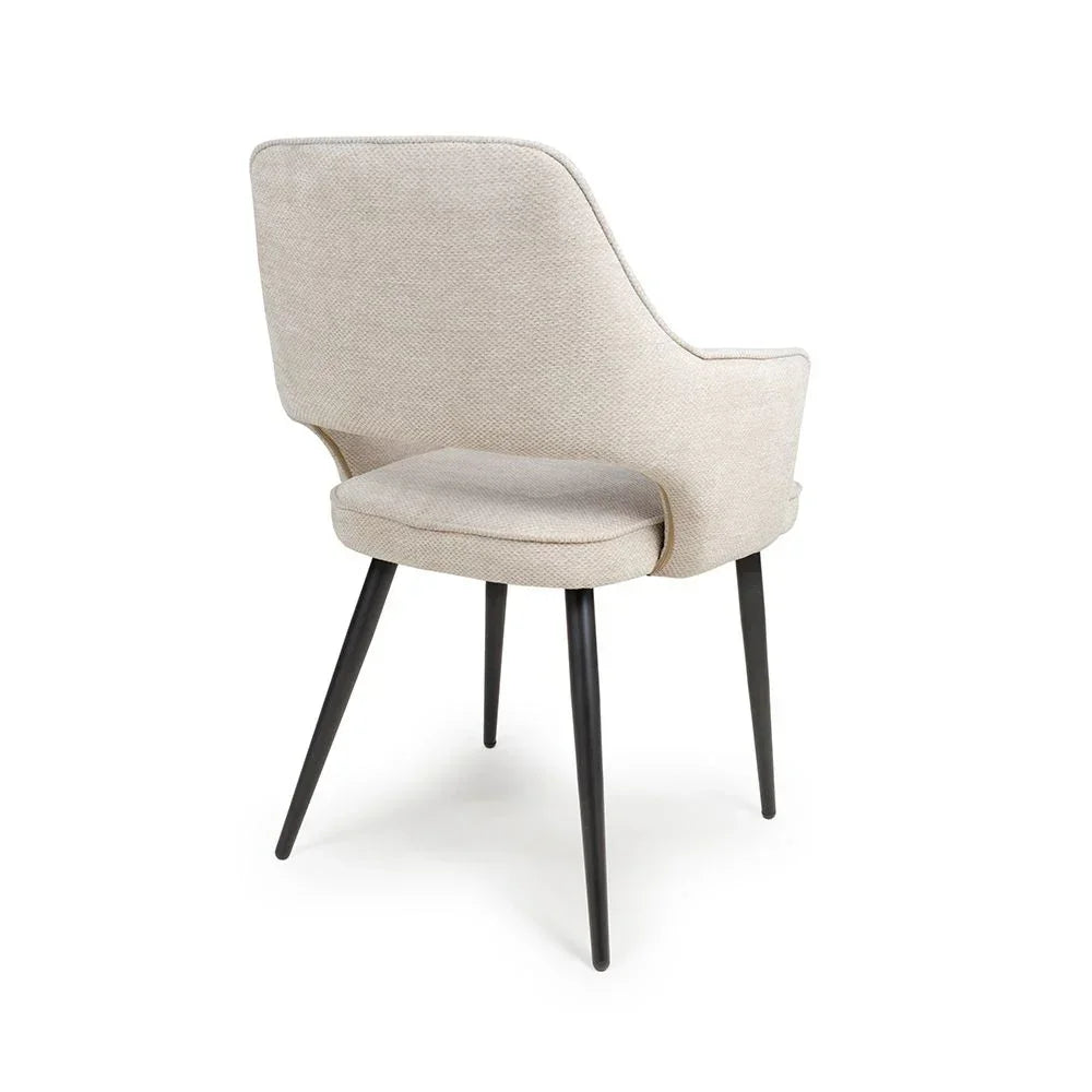 Beige upholstered dining chair with black angled legs, rear angle view