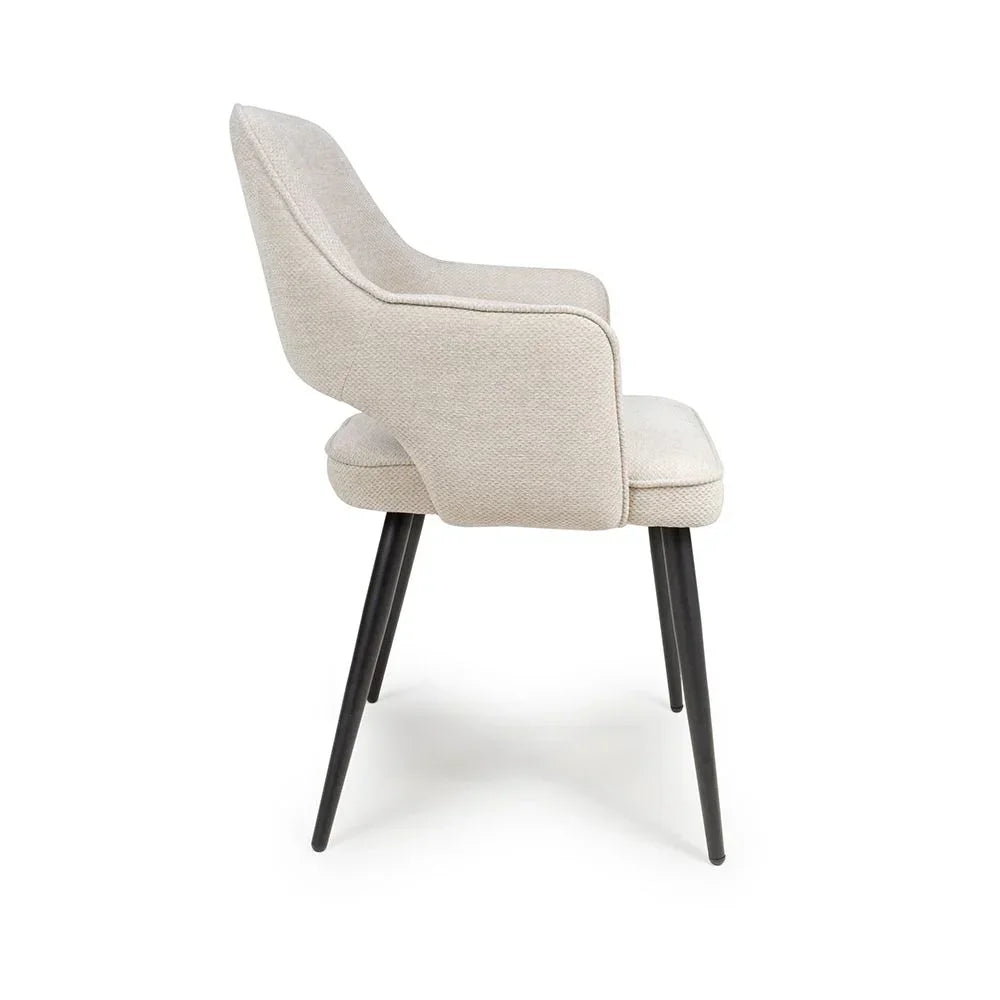 Beige fabric dining chair with slim black metal legs, side view