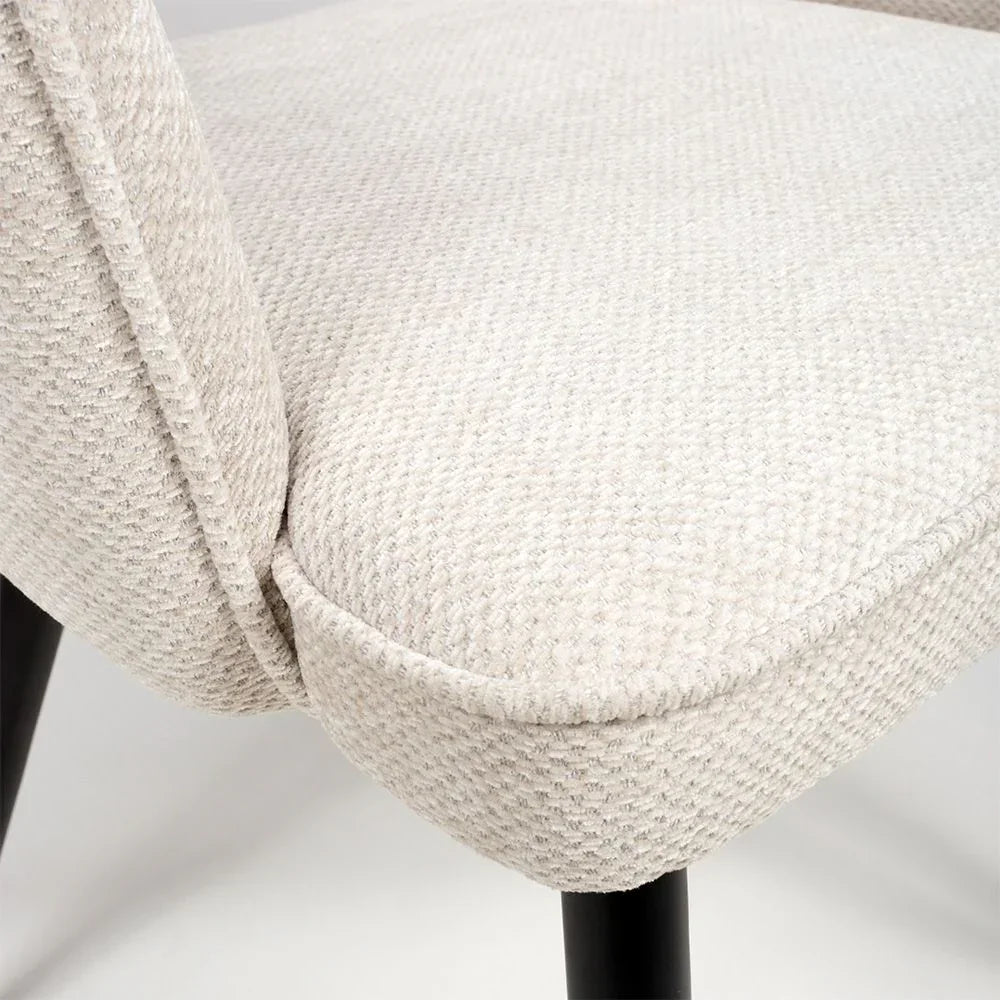 Cream fabric dining chair seat detail with textured upholstery and black leg