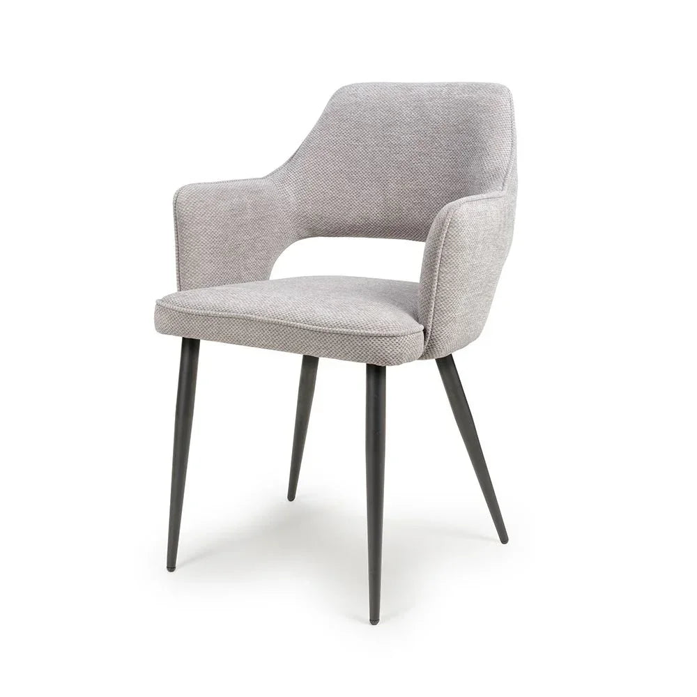 Grey fabric dining chair with armrests and black metal legs on white background