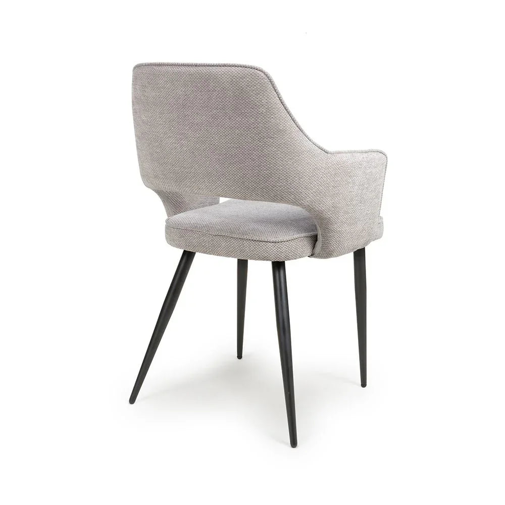 Grey upholstered dining chair with curved backrest and black tapered metal legs, rear angle