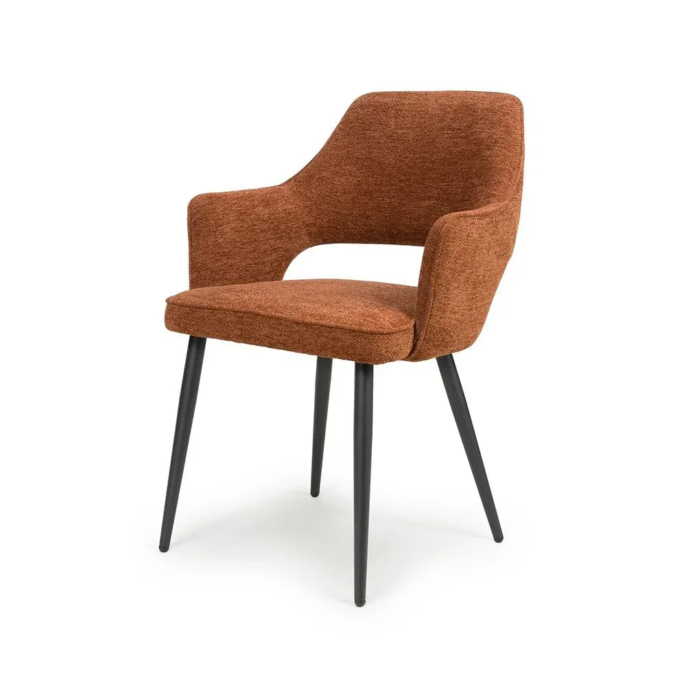 Rust fabric dining chair with armrests and black metal legs on white background