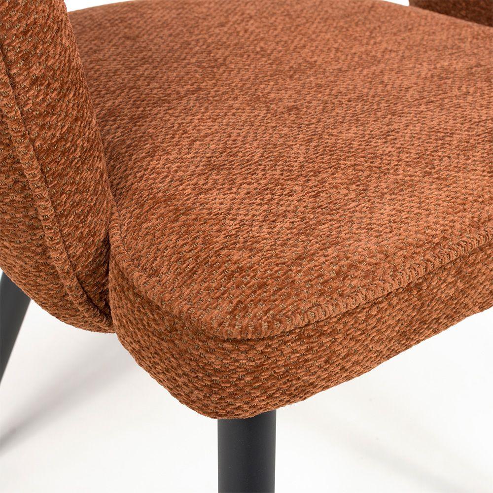 Close up of rust fabric dining chair seat with textured upholstery and black metal legs