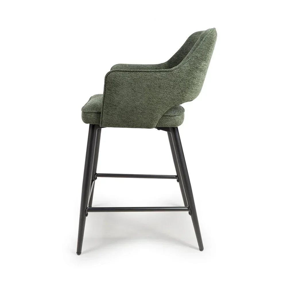 Green fabric bar stool with armrests and black metal legs, side view