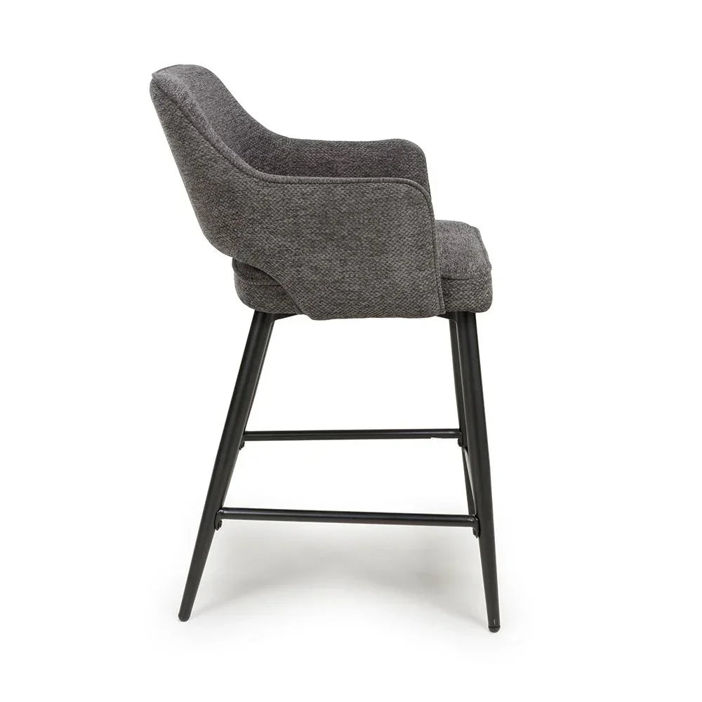 Grey fabric bar stool with black metal legs and armrests, side profile view