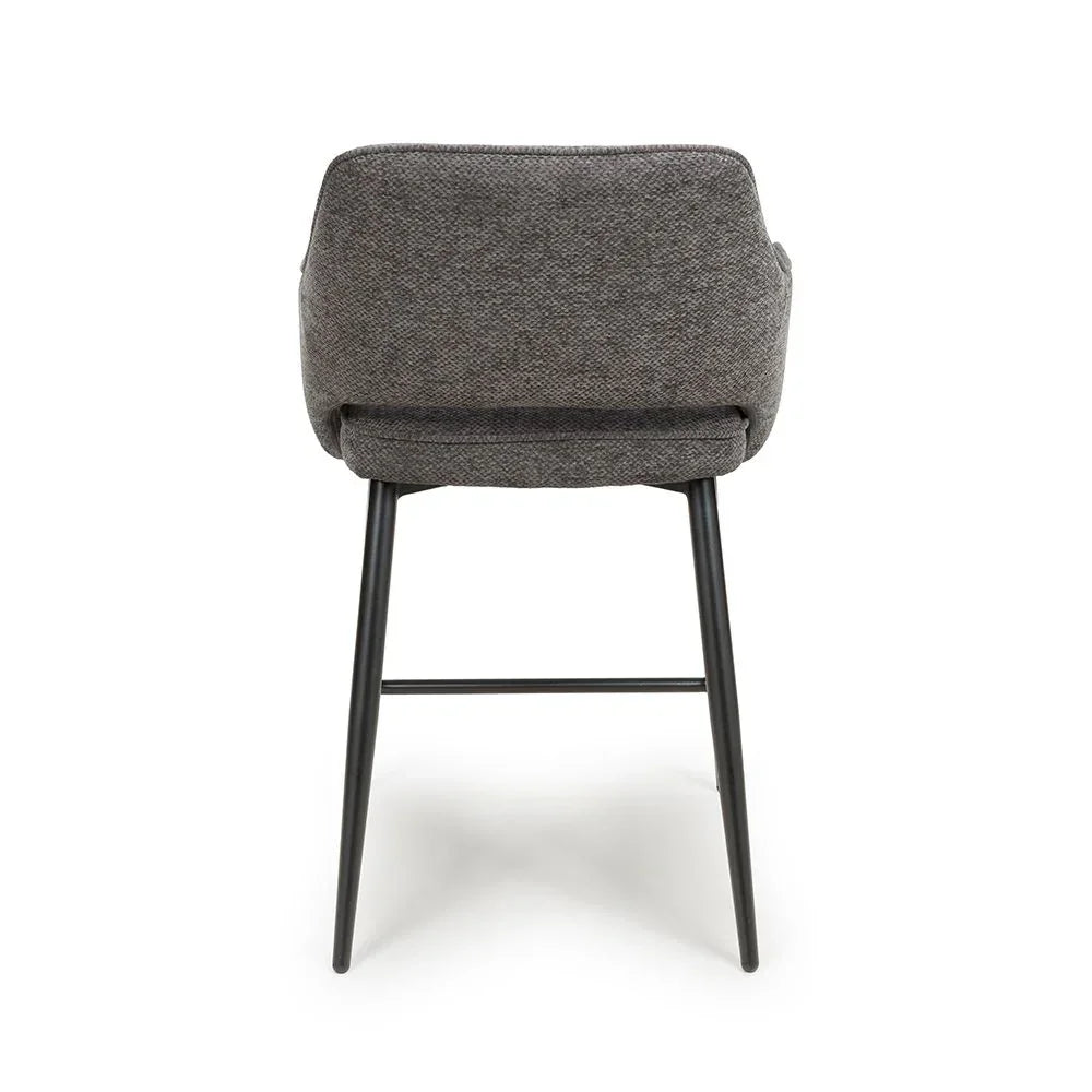 Rear view of grey upholstered dining chair with black metal legs