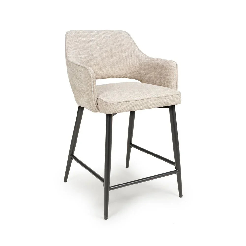 Beige upholstered bar stool with armrests and black metal legs on white background