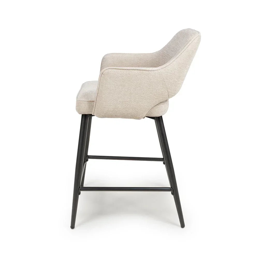 Beige upholstered dining chair with black metal legs side view