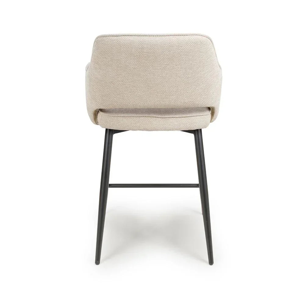 Beige fabric dining chair with curved backrest and black metal legs, rear view
