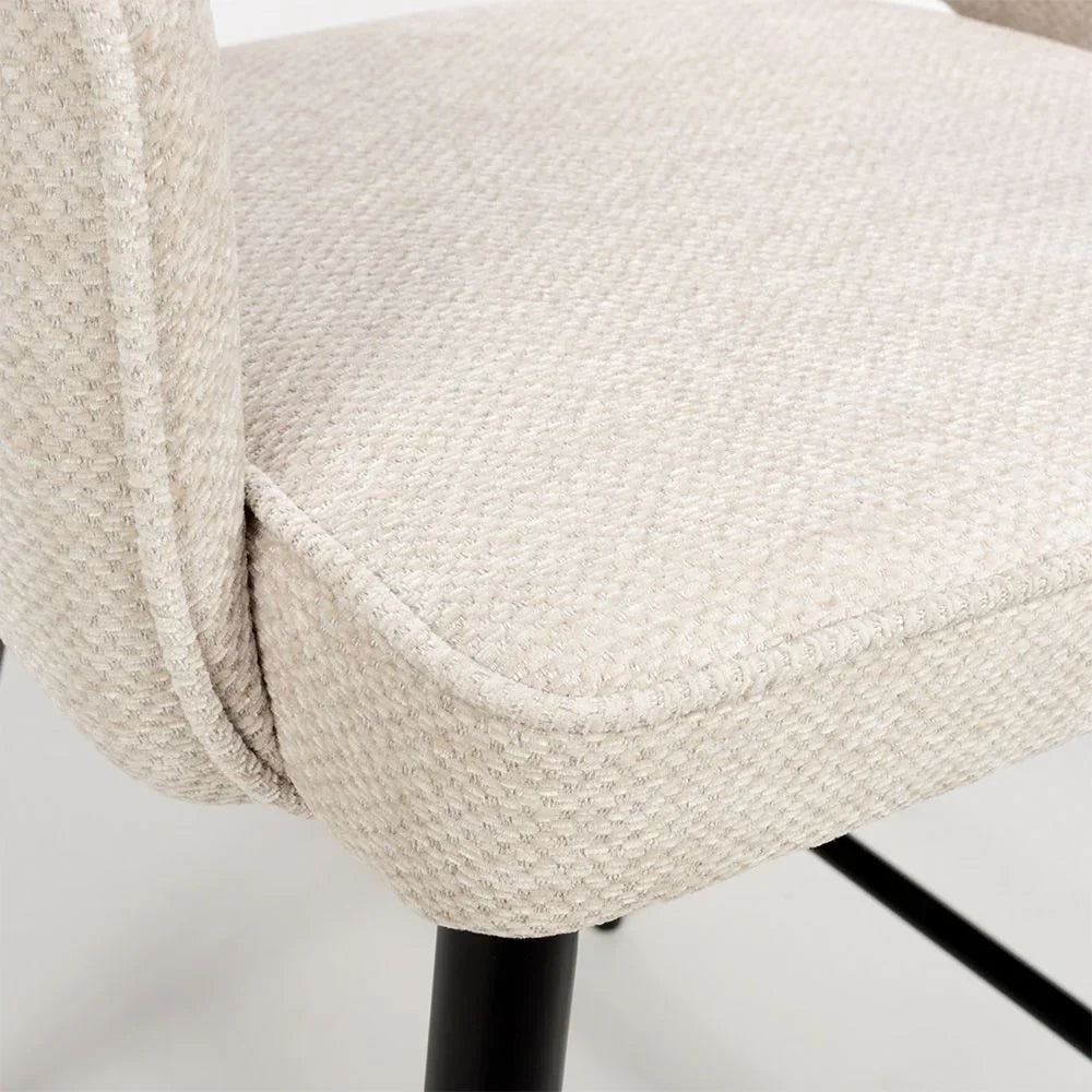 Close up of beige fabric dining chair seat with textured upholstery and black metal legs