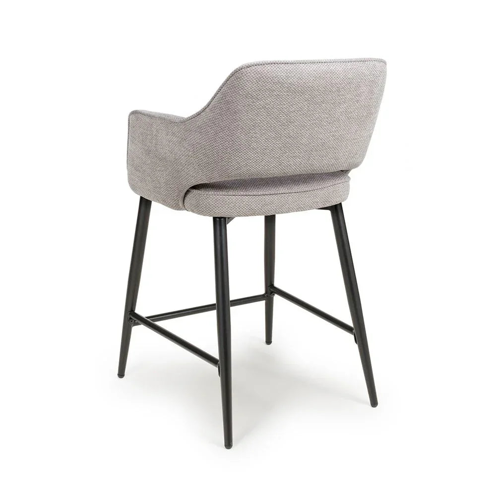 Grey upholstered bar stool with metal legs shown from rear angle