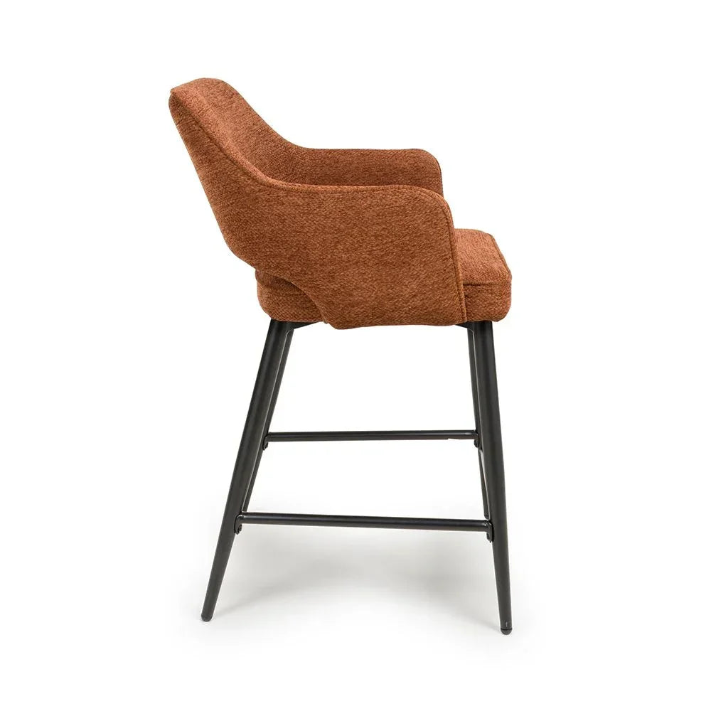 Rust fabric bar stool with armrests and black metal legs, side profile view