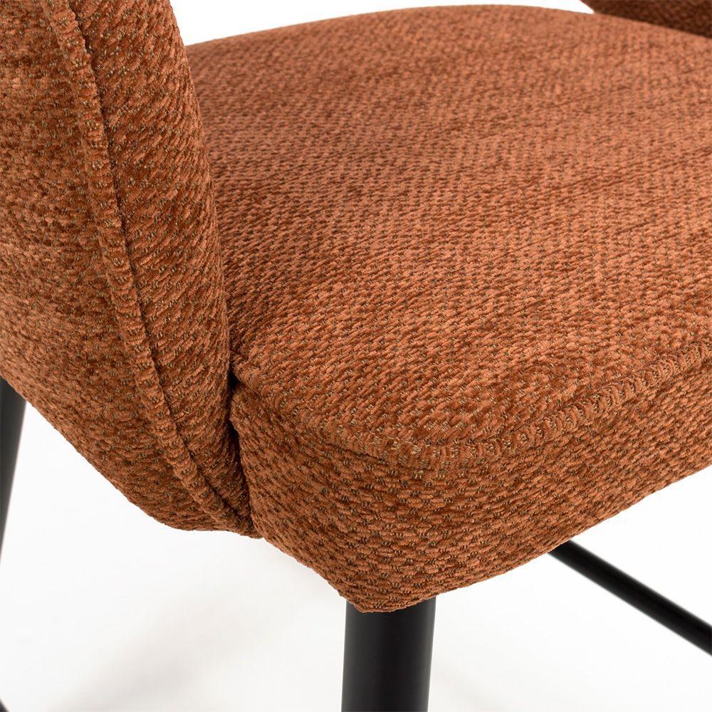 Rust textured fabric dining chair seat with black metal legs, close-up detail view