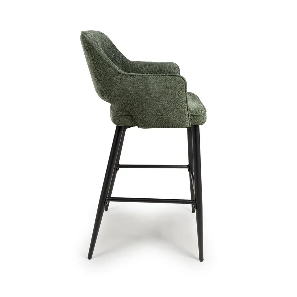 Green bar stool with upholstered seat, armrests, and black metal legs, side view
