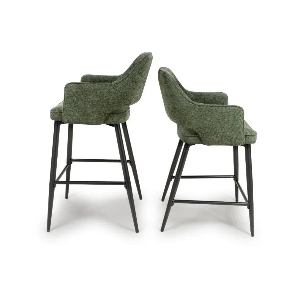 Pair of green fabric bar stools with armrests and black metal legs side by side