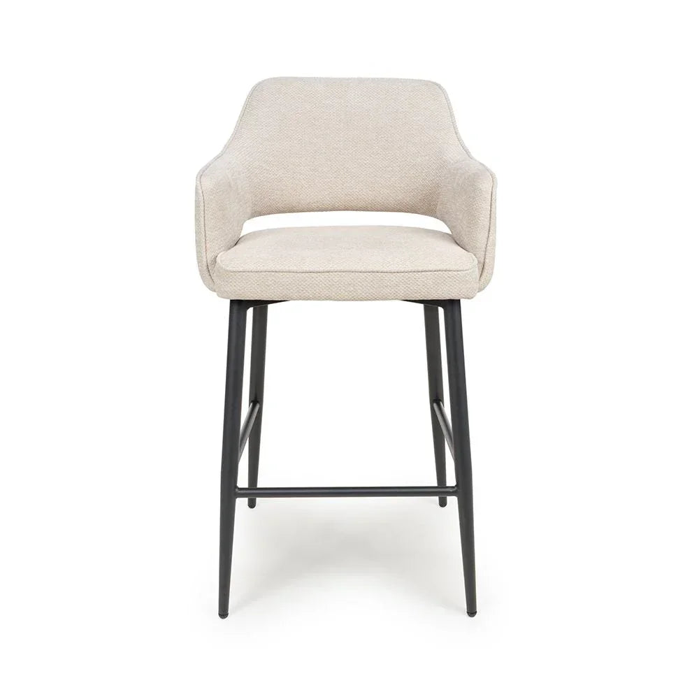 Beige upholstered bar stool with armrests and black metal legs, front view
