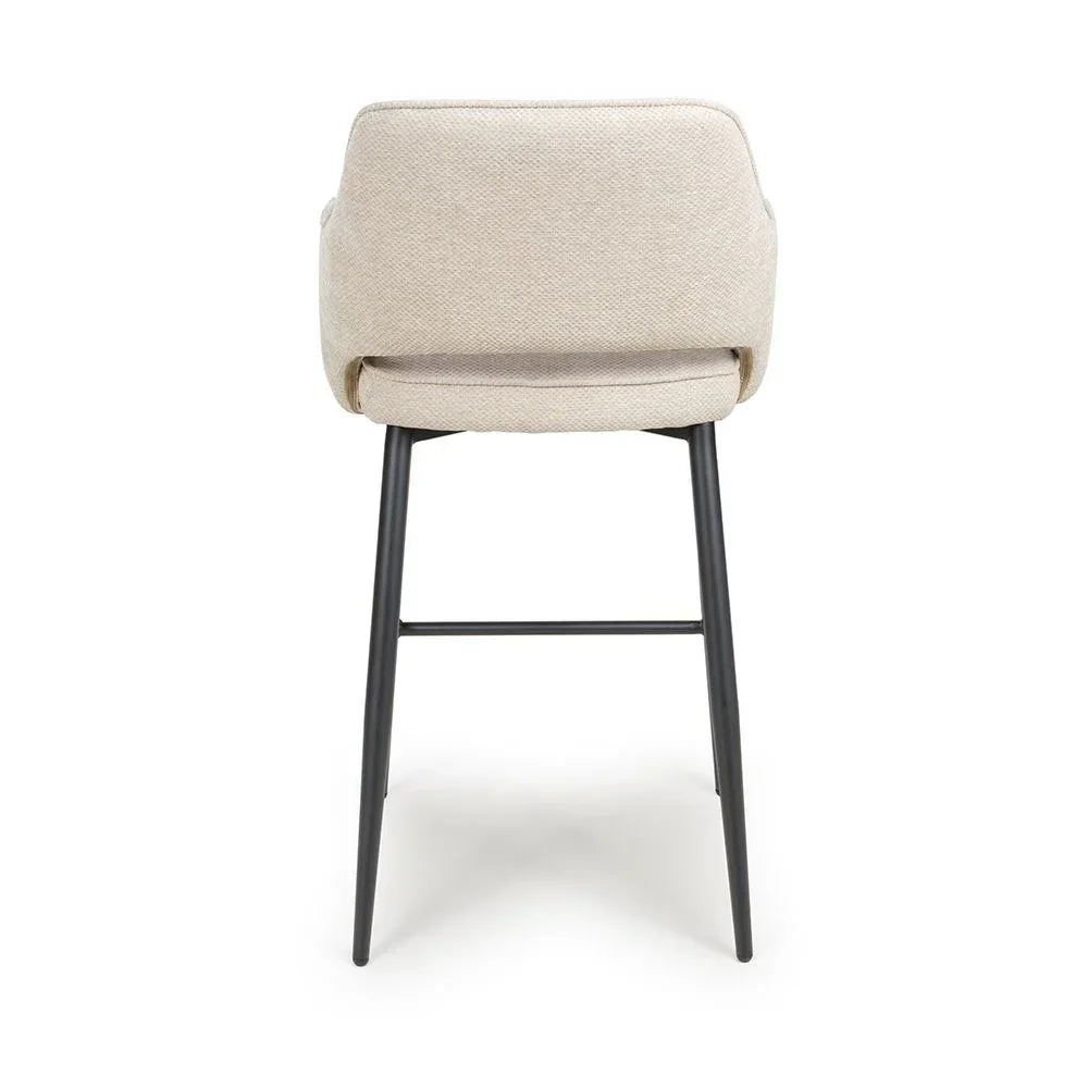 Beige fabric bar stool with curved backrest and black metal legs, rear view