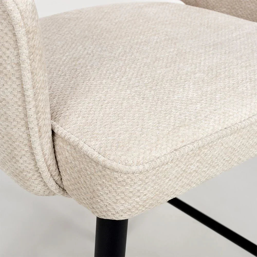 Beige fabric dining chair seat with black metal legs, close-up of upholstery texture