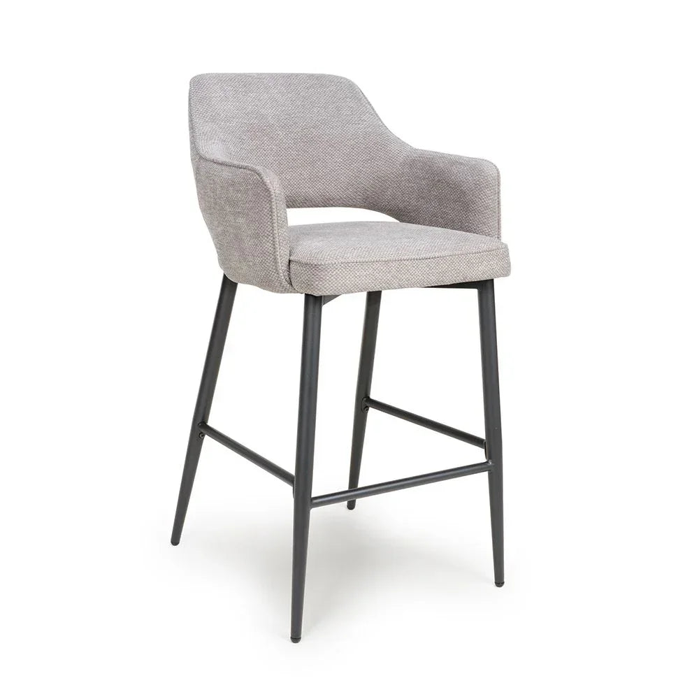 Light grey upholstered bar stool with black metal legs and armrests on white background
