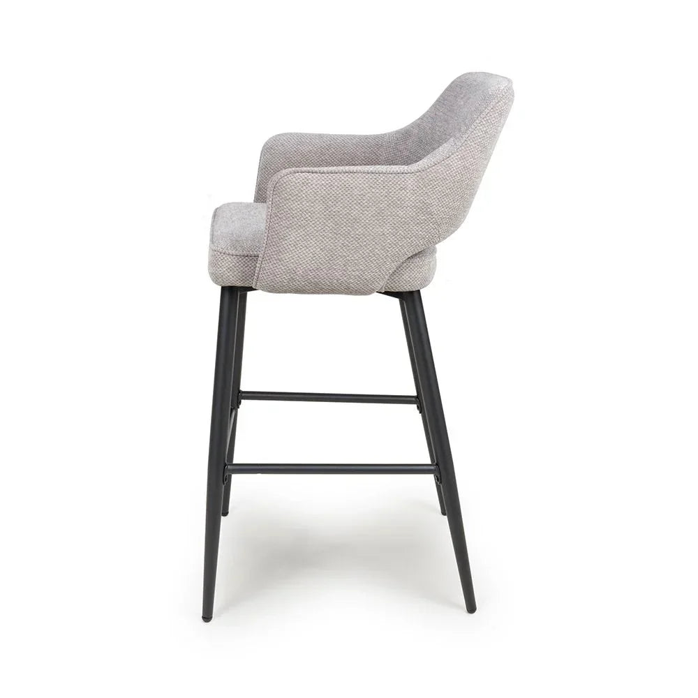Grey fabric bar stool with armrests and black metal legs, profile side view