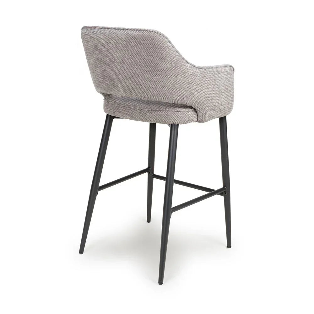 Grey fabric bar stool with black metal legs, angled rear view highlighting curved backrest