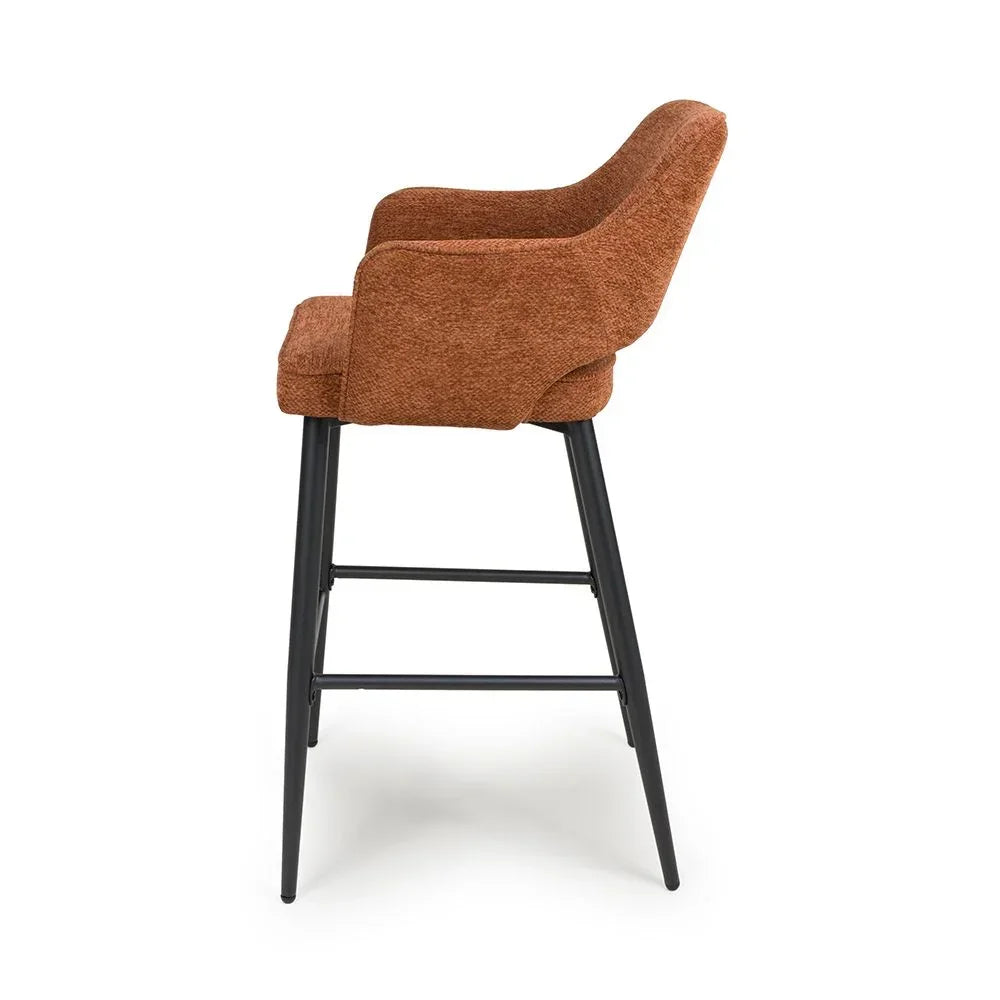 Rust fabric bar stool with padded seat, curved backrest and black metal legs, side view