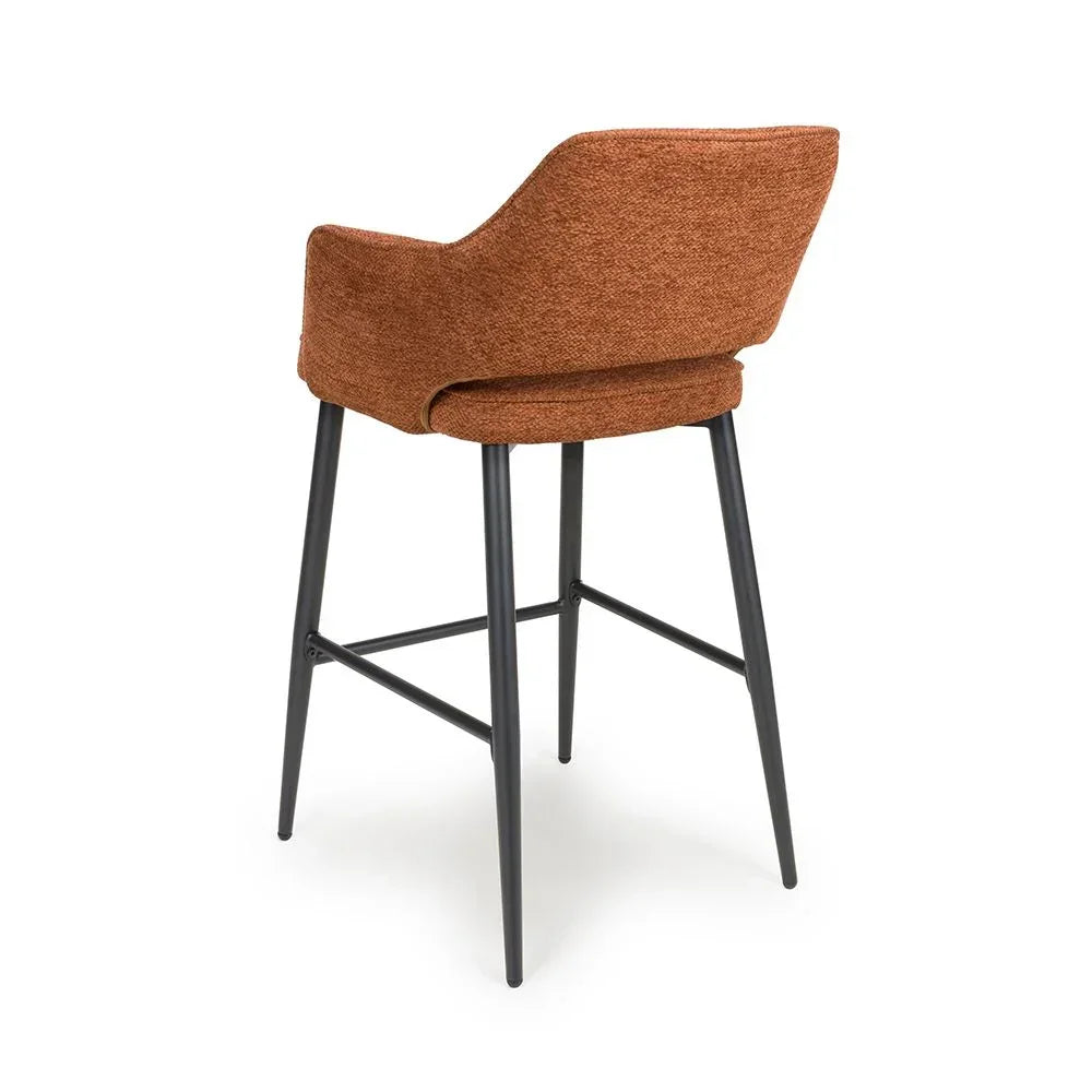 Rust fabric bar stool with curved backrest and black metal legs, rear angle view