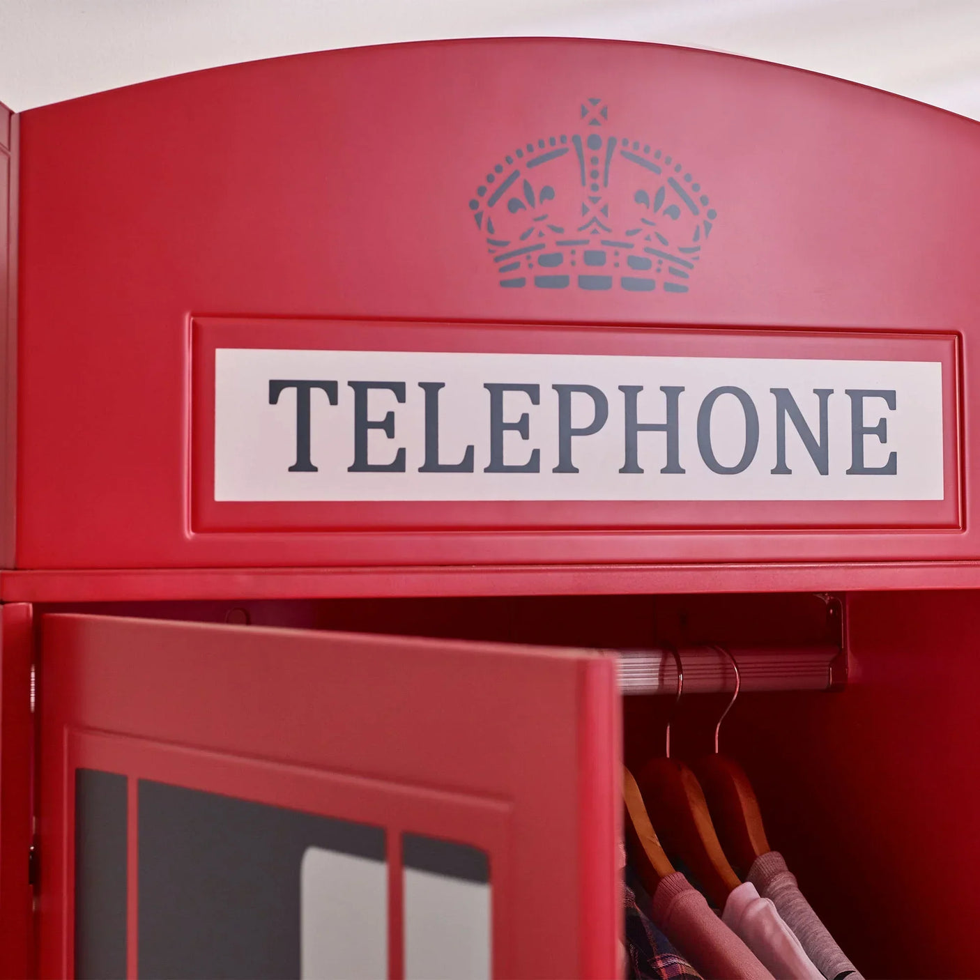 Red telephone box wardrobe detail with hanging rail and clothes on wooden hangers