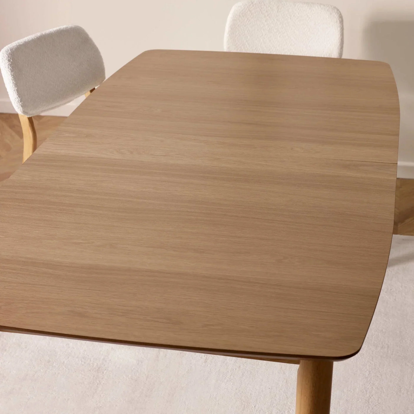 Rectangular wooden dining table with rounded edges and light upholstered chairs