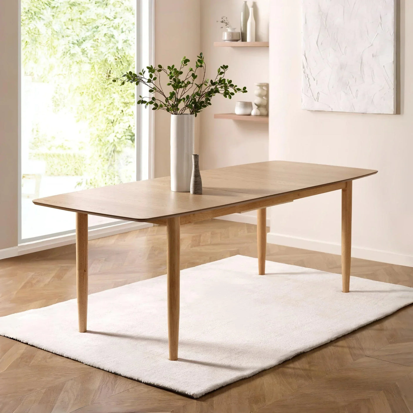Oak dining table on white rug with vases in bright modern room