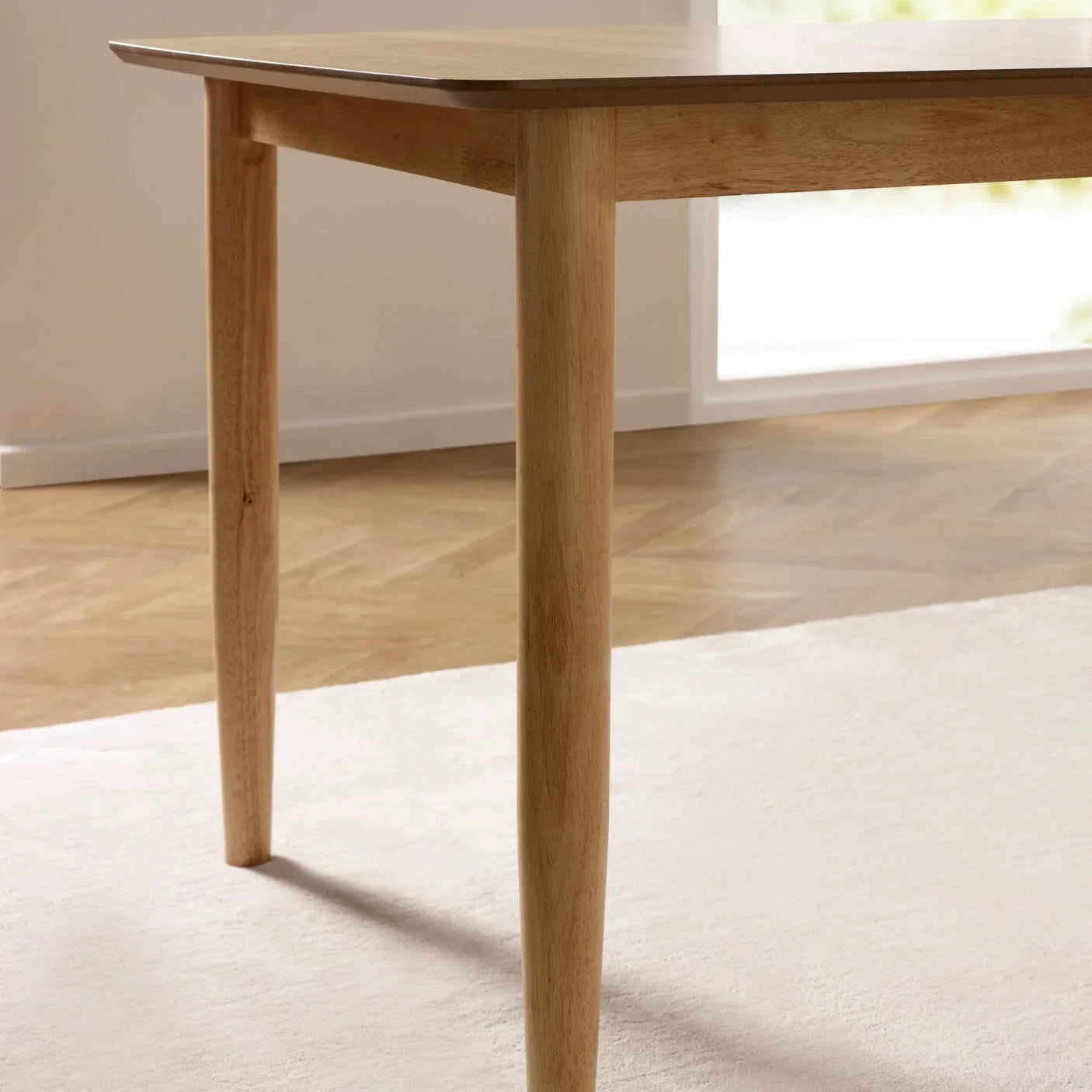 Light oak dining table corner with tapered legs on wooden floor