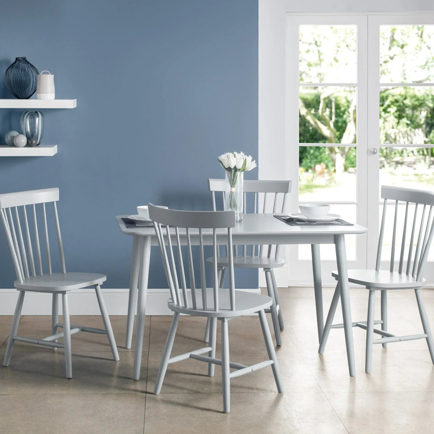 Light grey dining table with four matching spindle back chairs in a bright modern dining area