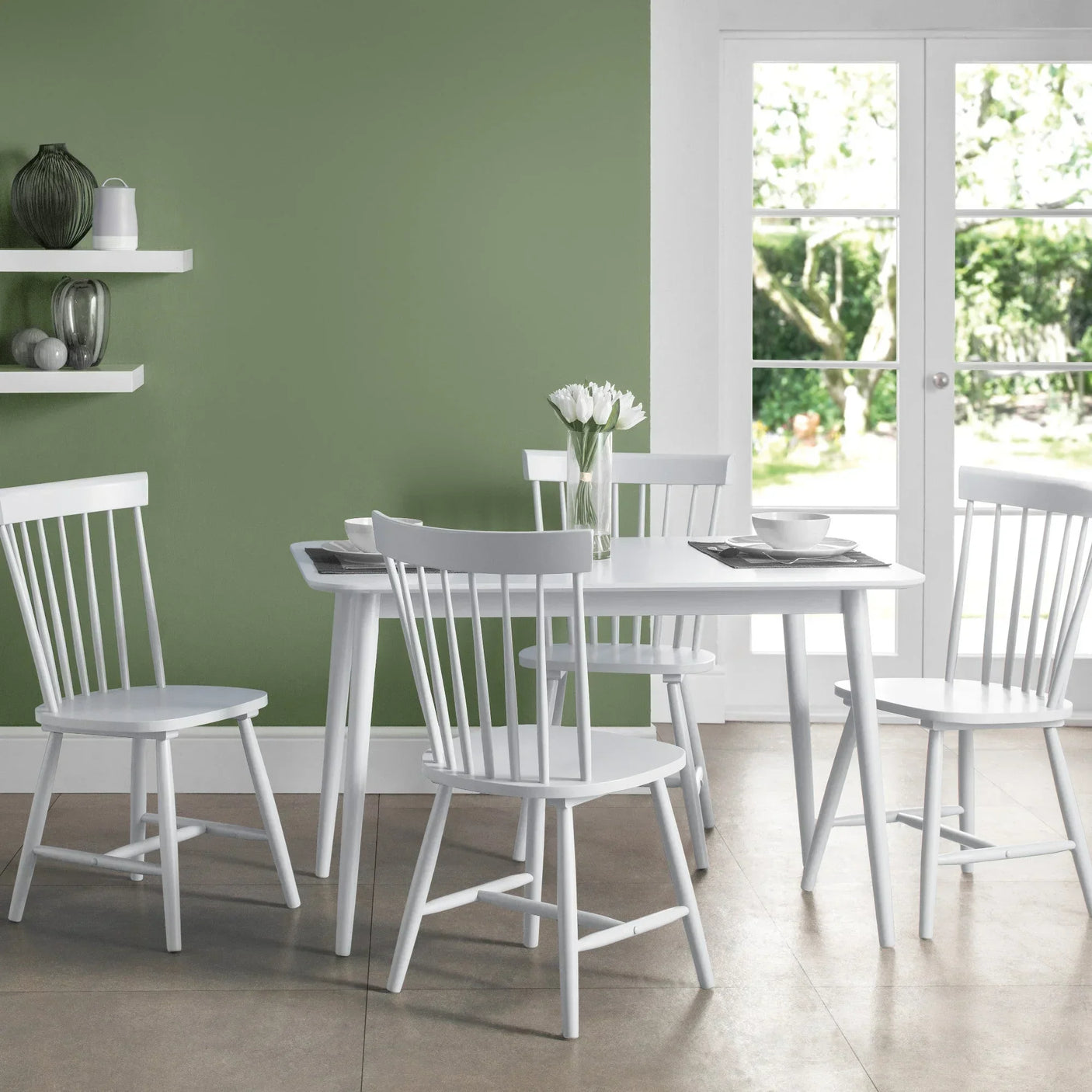White dining table set with four spindle back chairs in modern kitchen near patio doors