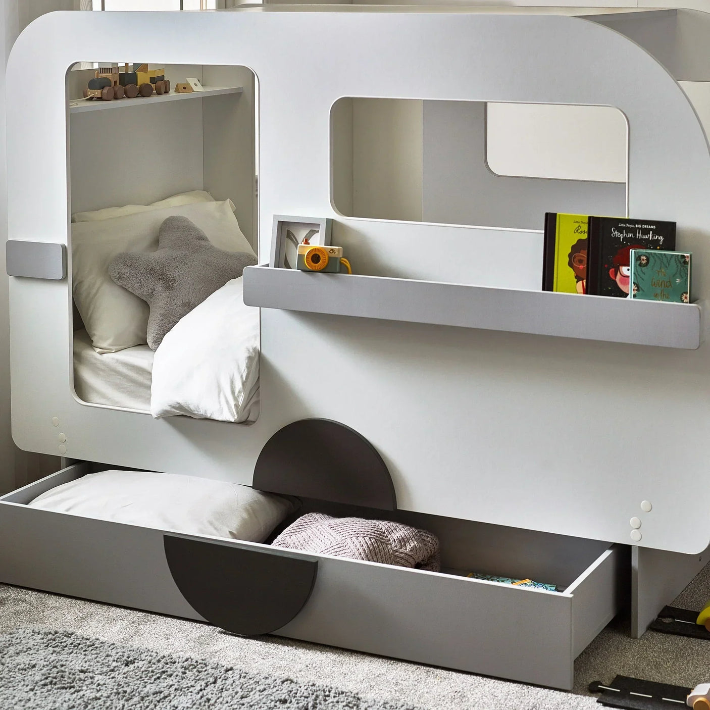 Tourer caravan bed with open storage drawer, books and star cushion