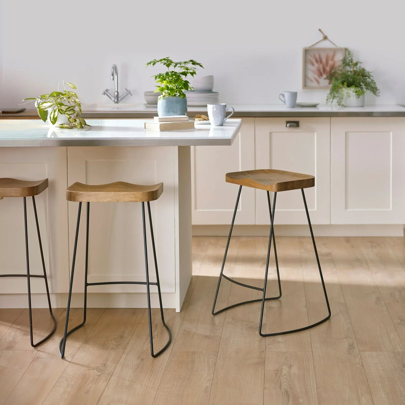 Solid oak bar stools with black metal legs at a light wood kitchen island
