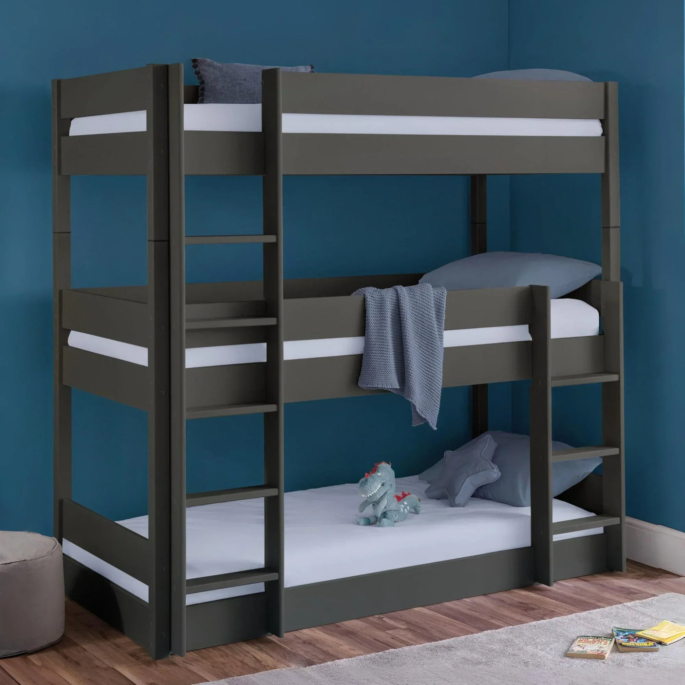 Grey wooden bunk bed with ladders in blue kids room, plush toy and books on floor