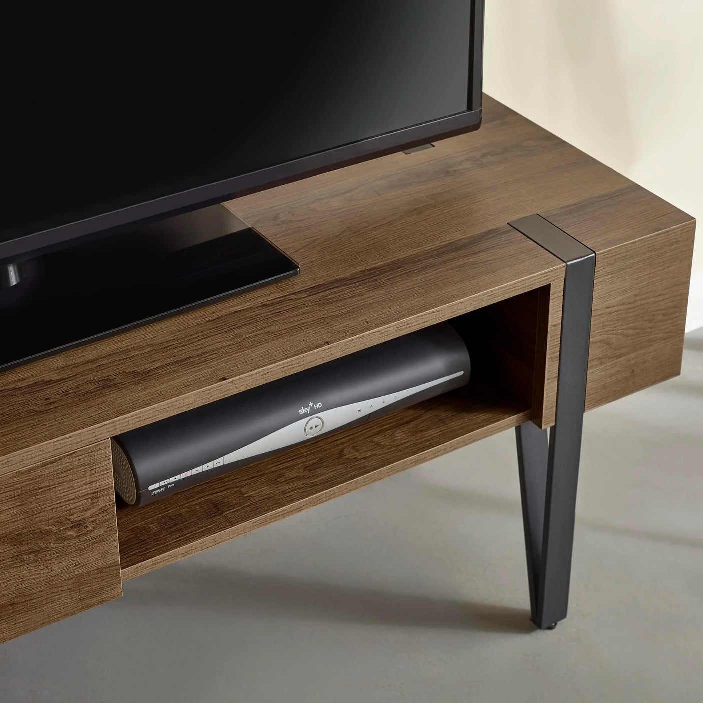 Wooden TV unit with open shelf and metal legs, housing a media box under the television