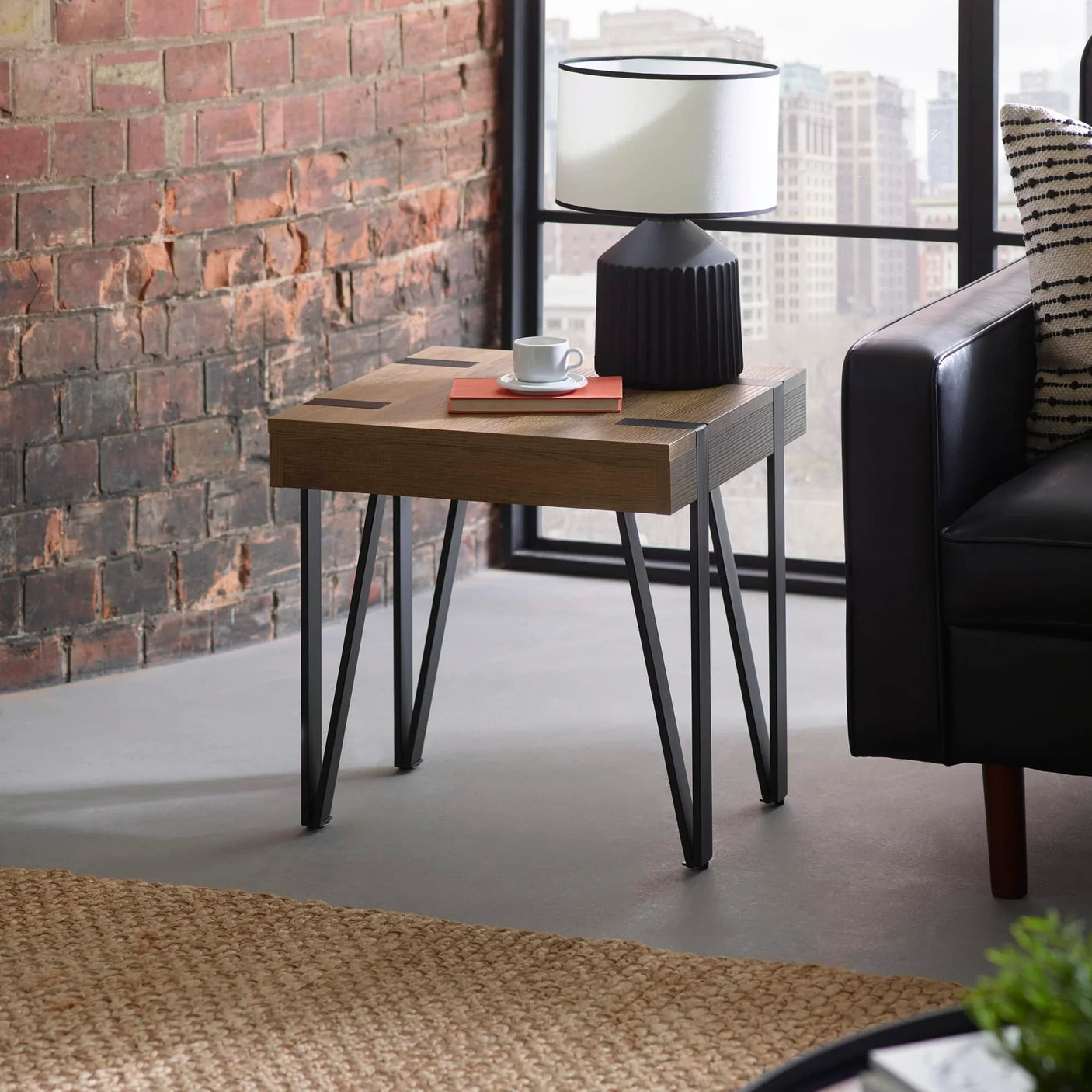 Oak side table with black metal legs, lamp and cup in modern living room setting