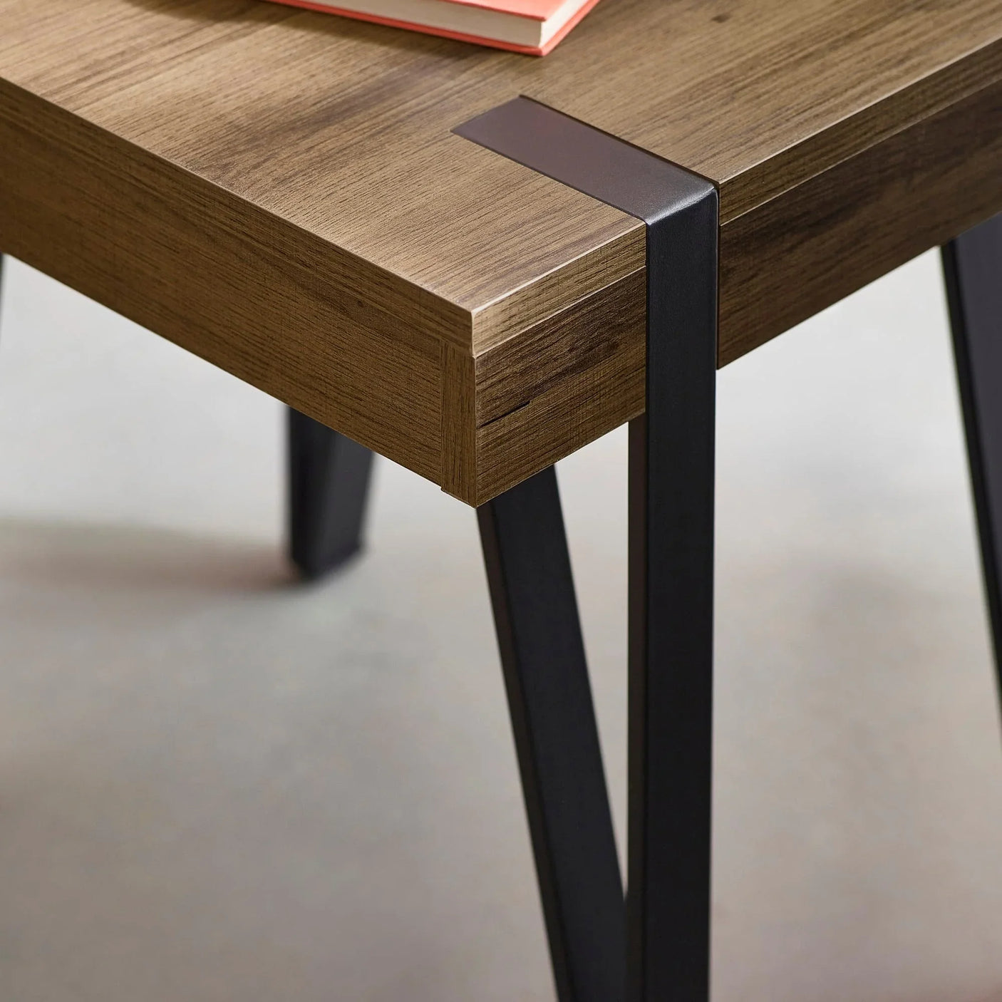 Wooden dining table corner with black metal legs and integrated metal corner detail