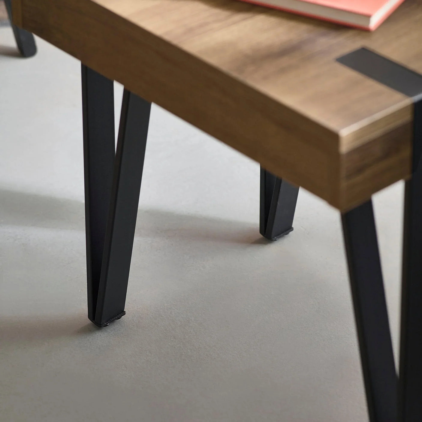 Wood dining table corner with black metal legs on light floor